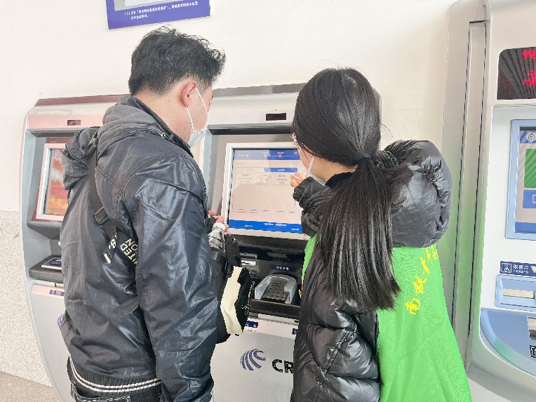 江西鹰潭北站，青年志愿者正在帮助旅客操作自助售票机。朱笑艺摄