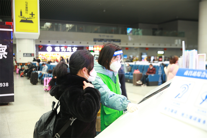 青年志愿者帮助旅客查询购票信息。张倩 摄