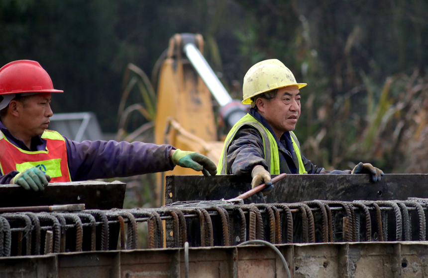 施工人员顶着阵阵毛雨在古阳寨桥梁建筑工地作业。何贱来摄