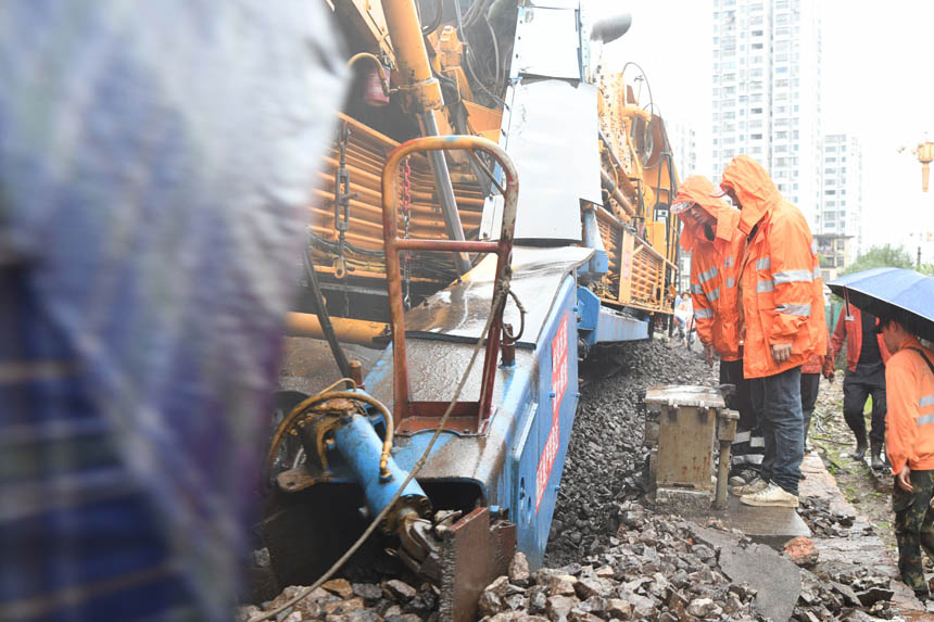 中国铁路南昌局集团有限公司福州电务段职工在雨中盯控大机清筛旁的信号设备。姜振涛摄