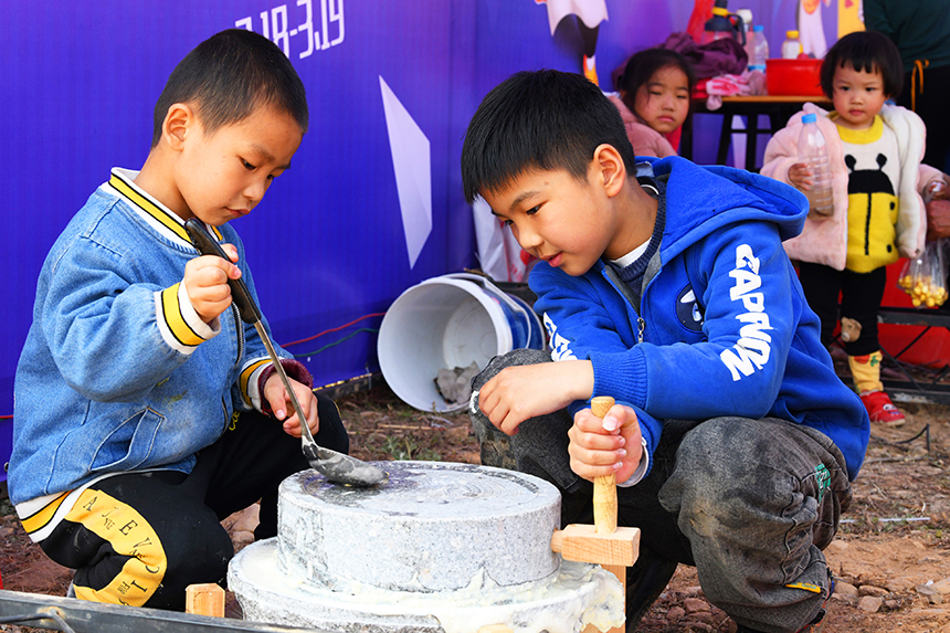 小朋友在用石磨磨豆腐，感受传统农事活动，享受美好春光。
