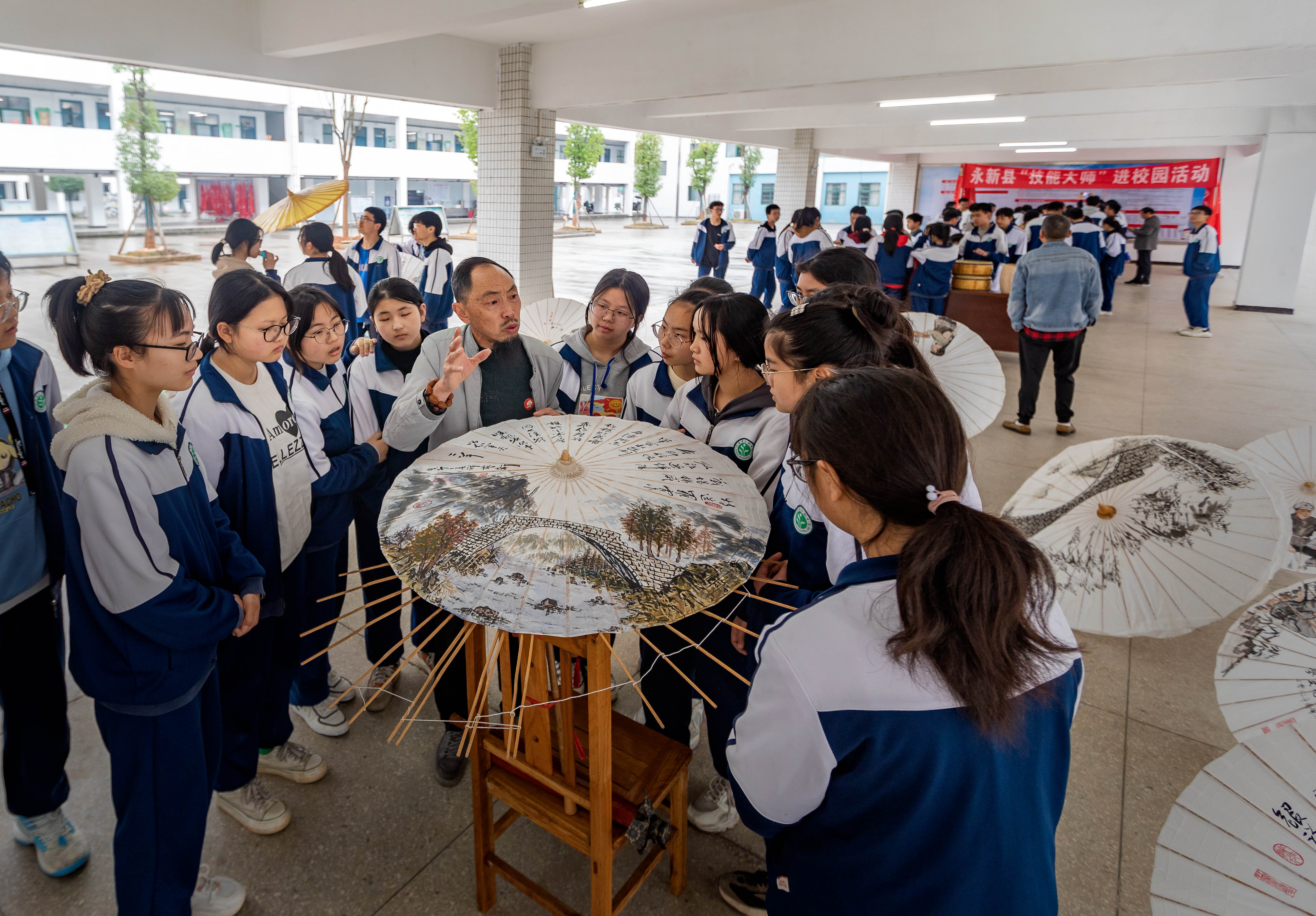 当地油纸伞制作技能大师在向孩子们讲解油纸伞的制作技艺。王惠民摄
