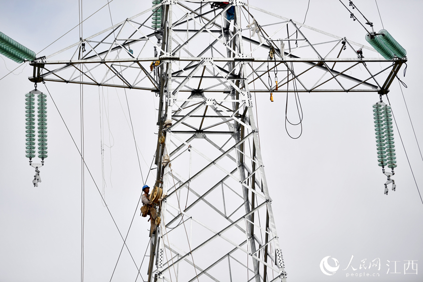 电网工作人员正在塔顶进行牵线作业。人民网 时雨摄