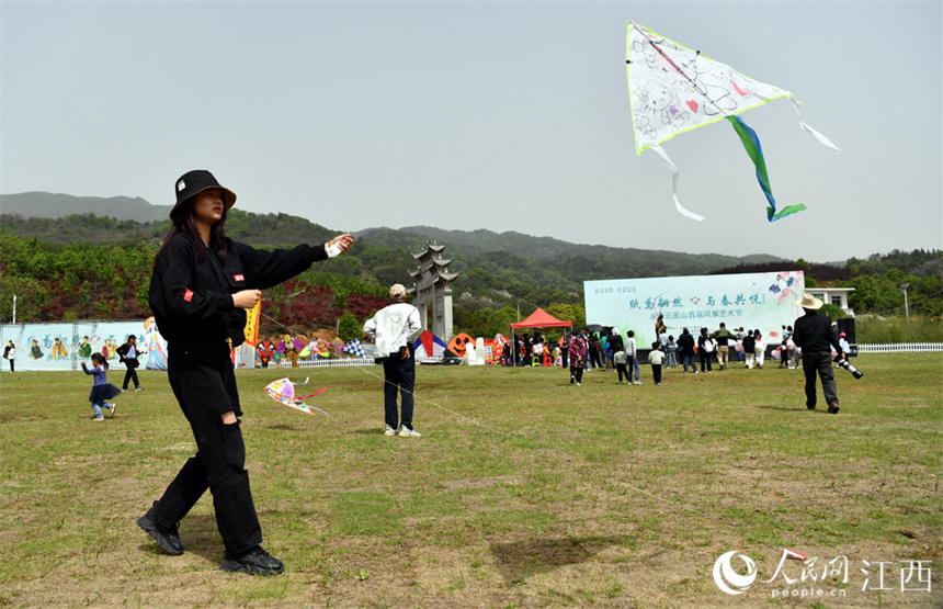 春日暖阳下，人们在草坪上放风筝。 人民网 时雨摄