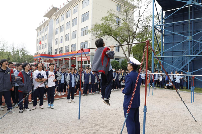 消防员指导学生进行单杠练习。蓝永贵摄