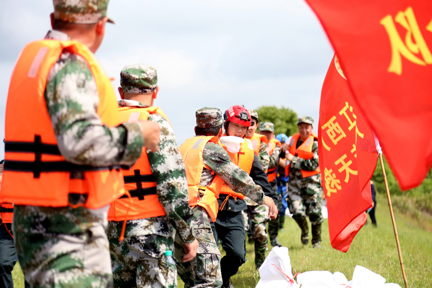 4月20日，广昌县防汛抢险应急演练在该县甘竹镇沿旴江河龙王坑河堤段举行，参演人员正在扛运沙袋，进行圩堤加固并搭筑子堤。地方供图