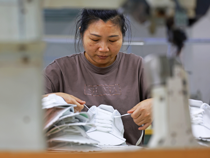 在丰城思维琦鞋服有限公司生产车间，工人们正在开足马力生产鞋服产品，满足订单需求。王堃摄