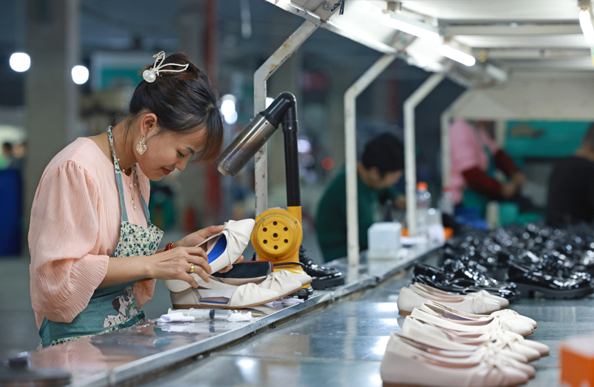 工人们正在开足马力生产鞋服产品，满足订单需求。王堃摄