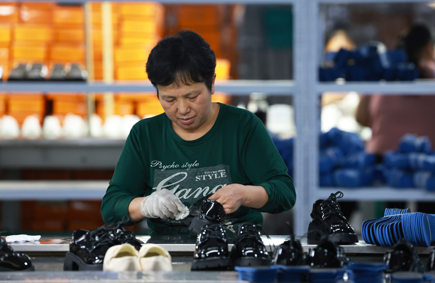 工人们正在开足马力生产鞋服产品，满足订单需求。王堃摄