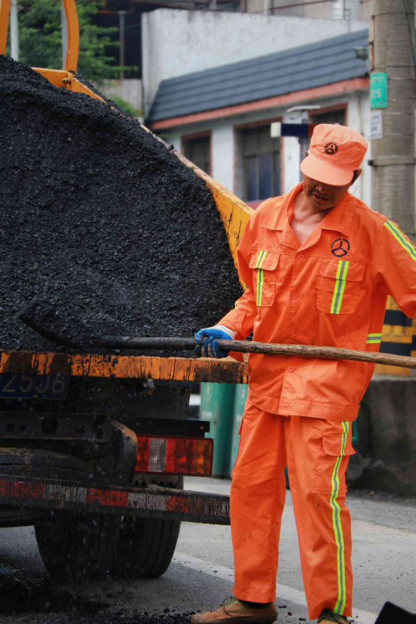 4月30日，公路養護工人把鋪柏油路的石子鏟下來填坑。李禹洪攝