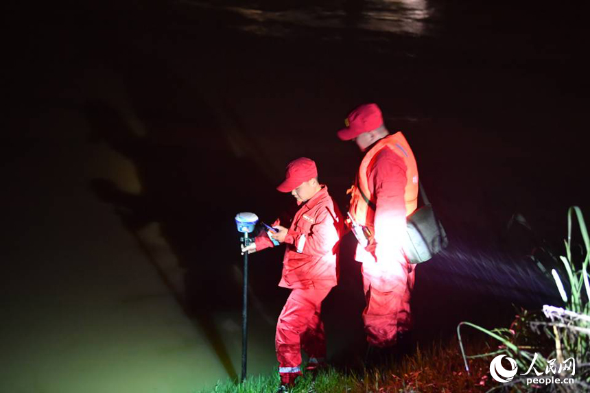 救援人員使用手持式流速儀監測潰口處表面流速。 人民網記者 時雨攝