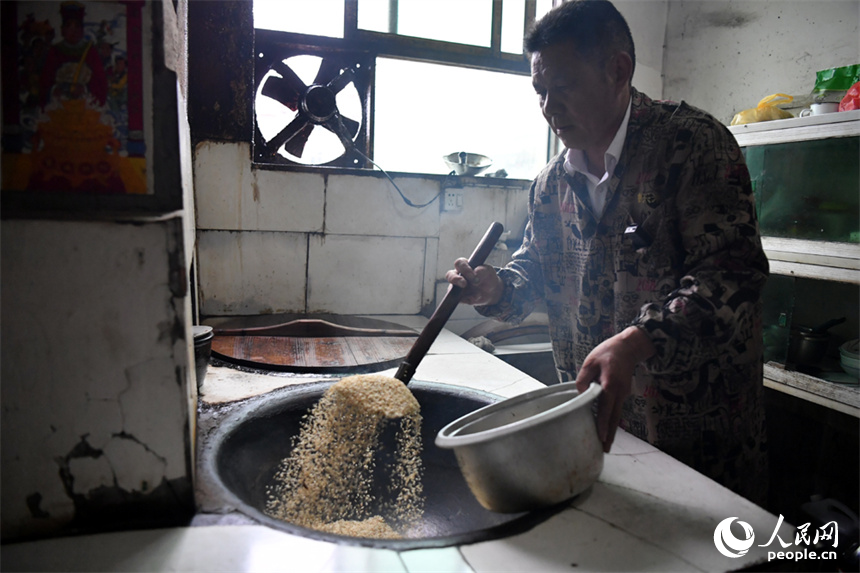 廖連榮在炒制早稻米。 人民網記者 時雨攝
