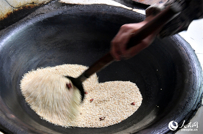 廖連榮在炒制早稻米。 人民網記者 時雨攝