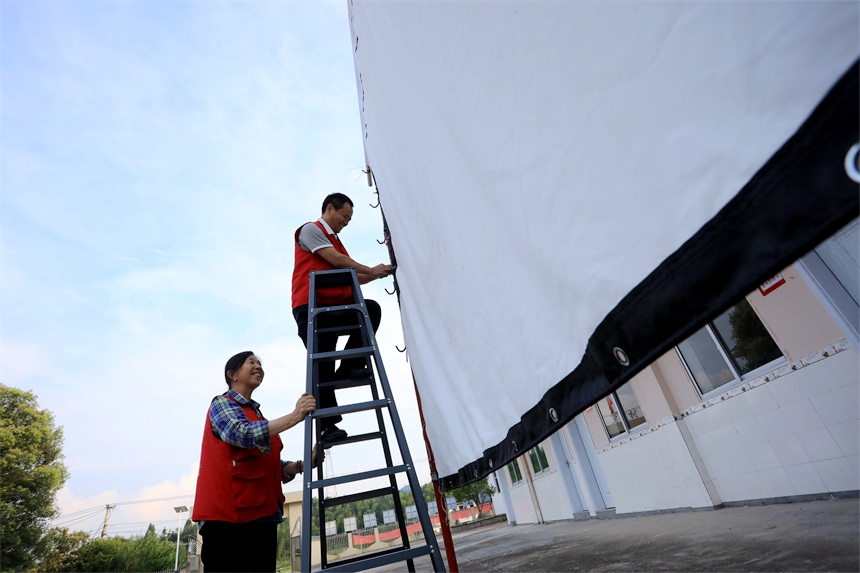 2023年6月14日，江西省抚州市乐安县鳌溪镇下罗村，志愿者们正在悬挂电影放映帆布。