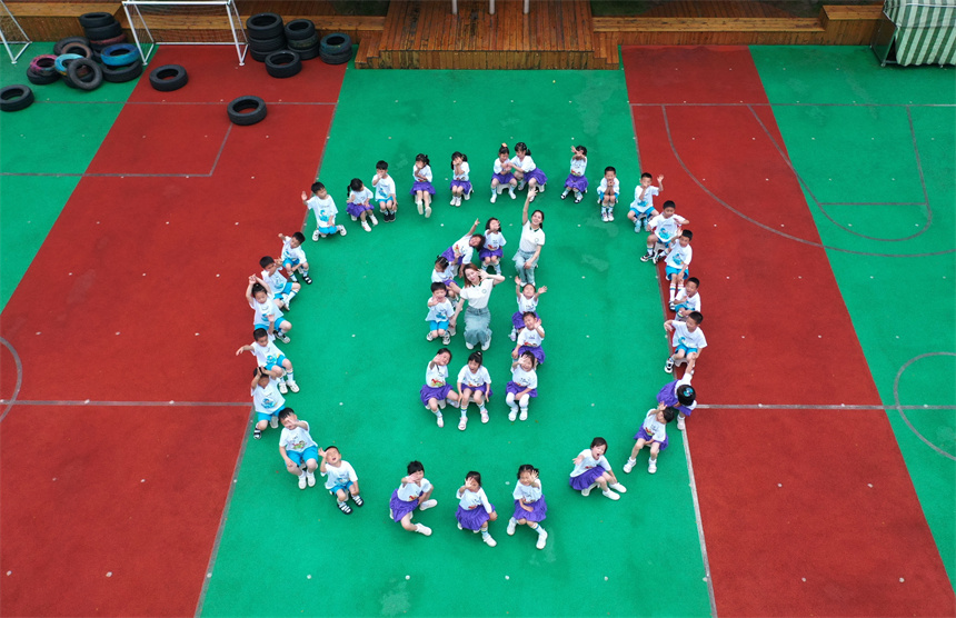 幼兒園師生們擺出創意造型，拍攝校園畢業照。 饒方其攝