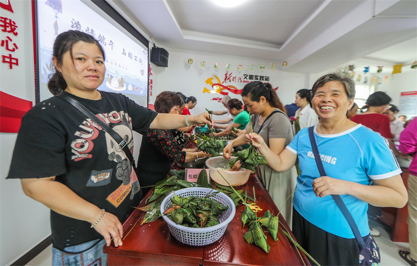 社区干部和居民志愿者正在社区开心地包粽子。
