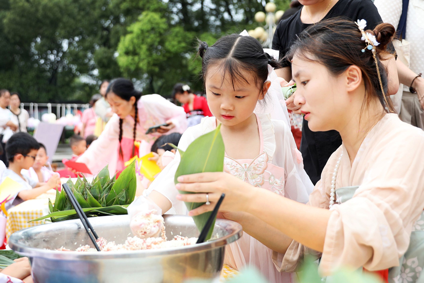 近日，江西省宜春市上高县镜山广场，县第二幼儿园的老师正在教孩子们包粽子。陈旗海摄