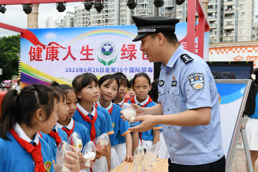 禁毒宣传活动现场，公安民警向学生们展示毒品仿真物，并讲解毒品所带来的危害。邓鹏摄