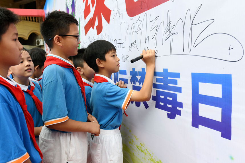 禁毒宣传活动现场，学生们纷纷在签名墙上签字，并表示要坚决远离毒品。邓鹏摄