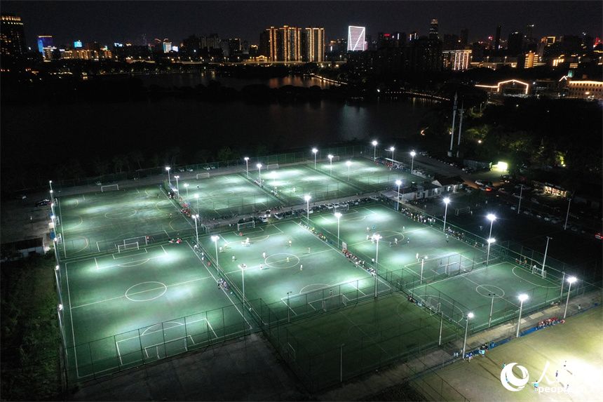 夏夜灯光下，足球爱好者们在球场内驰骋比拼。 人民网记者 时雨摄