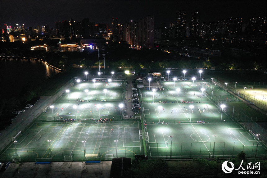 夏夜灯光下，足球爱好者们在球场内驰骋比拼。 人民网记者 时雨摄