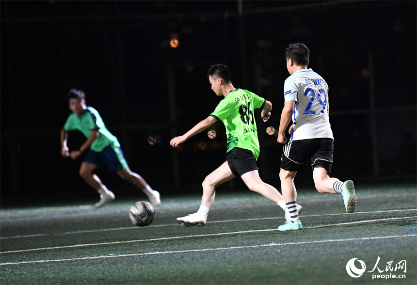 夏夜灯光下，足球爱好者们在球场内驰骋比拼。 人民网记者 时雨摄