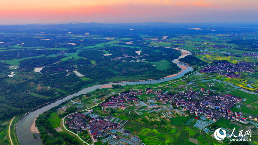 崇仁县巴山镇永红村，农房与蜿蜒河流相映衬，构成一幅色彩斑斓的夏日乡村画卷。人民网 朱海鹏摄