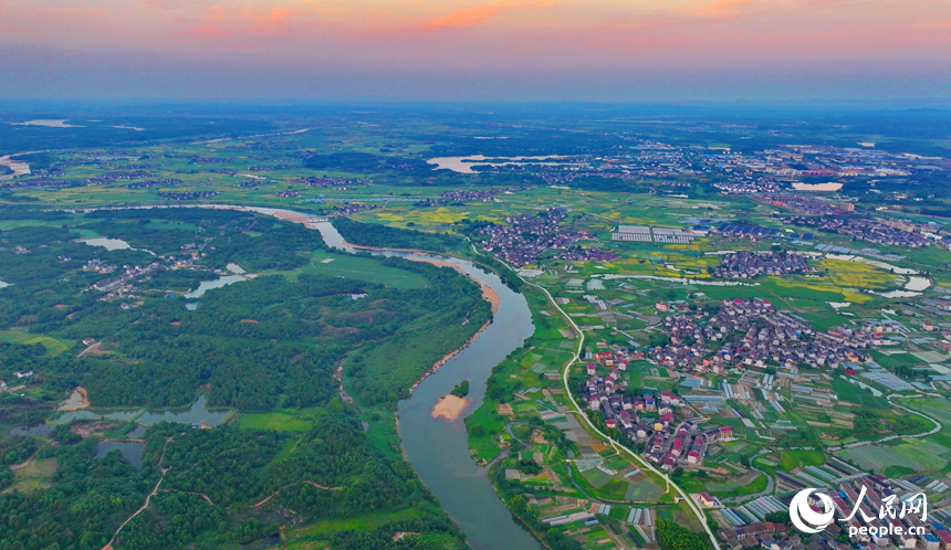 崇仁县巴山镇永红村，农房与蜿蜒河流相映衬，构成一幅色彩斑斓的夏日乡村画卷。人民网 朱海鹏摄