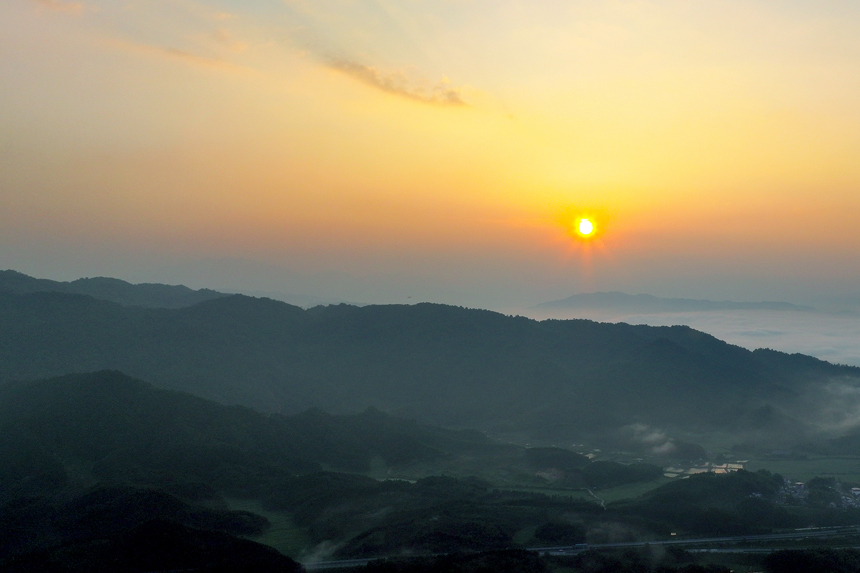 一轮红日从云雾缭绕的连绵山峦冉冉升起，构成一幅生态画卷。何贱来摄