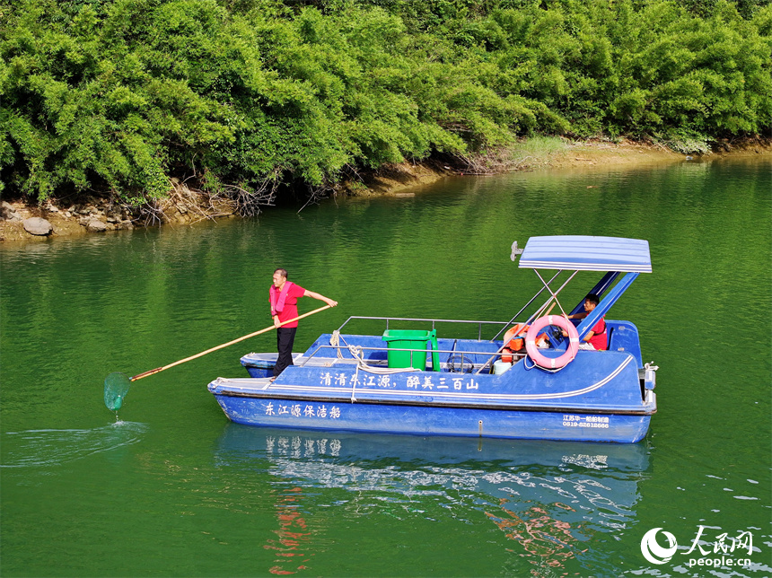 近日，江西省贛州市安遠縣三百山東風湖，生態保潔員駕駛保潔船在清理水面漂浮物。人民網 朱海鵬攝
