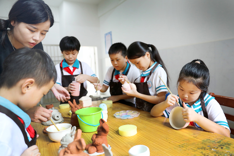 孩子們在老師的指導下給陶瓷上釉。陳旗海攝