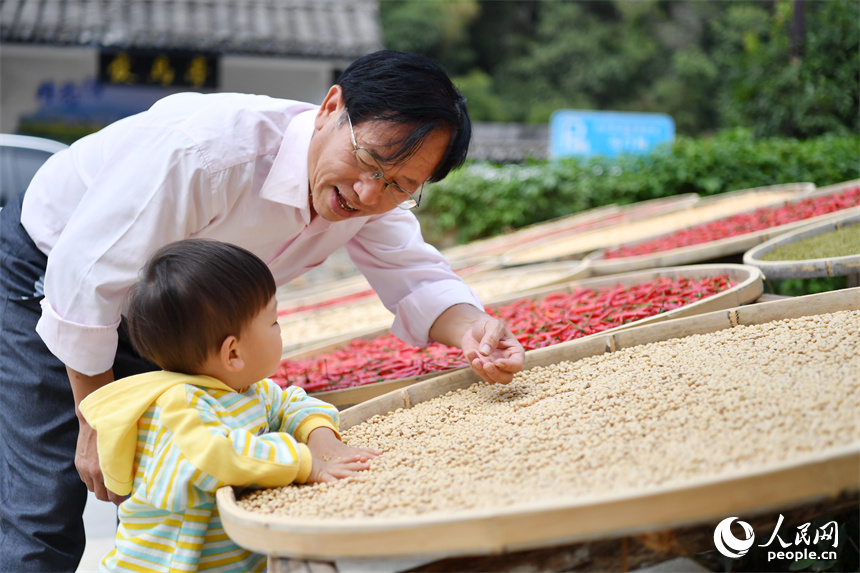 一位游客正在教孩子識別晒匾中的農作物。 人民網記者 時雨攝