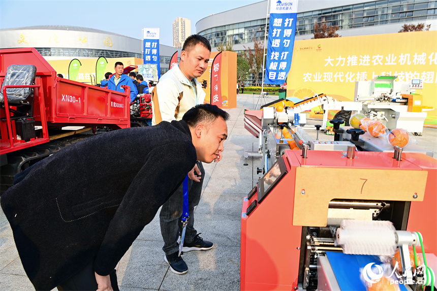 观展群众在了解脐橙种植、分选、清洗设备和农资。人民网 朱海鹏摄