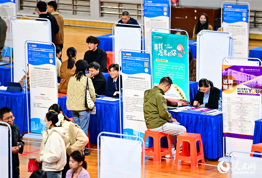 毕业生在招聘会了解咨询招聘信息，与招聘单位、企业负责人进行一对一洽谈沟通。人民网 朱海鹏摄