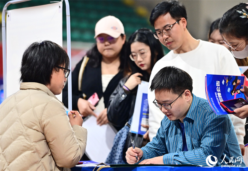 毕业生在招聘会了解咨询招聘信息，与招聘单位、企业负责人进行一对一洽谈沟通。人民网 朱海鹏摄