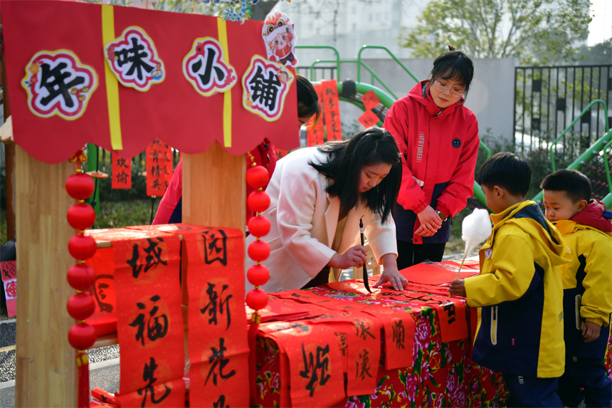 幼儿家长在“庙会集市”泼墨挥毫写对联。时雨摄