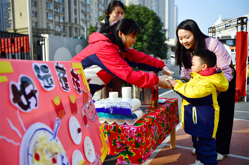 老师在“庙会集市”向幼儿们分发美食。时雨摄
