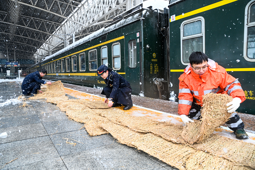 南昌站工作人员为即将上车的旅客铺设防滑草垫。刘慕 摄