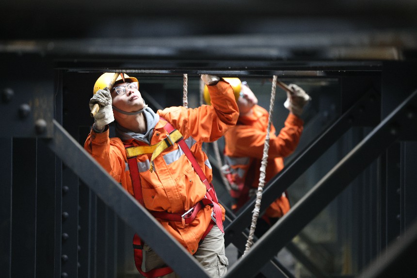 桥隧工们对钢梁桥连结处螺栓敲击检查。潘友南摄