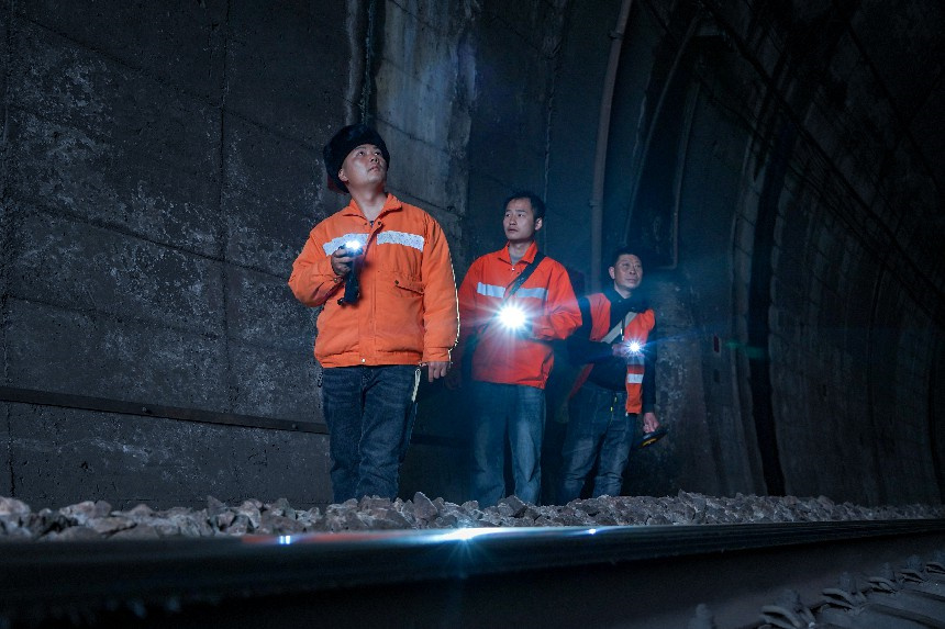 隧道内的路肩只能容一人通过，桥隧工成列逐米排查隧道病害。罗毅摄