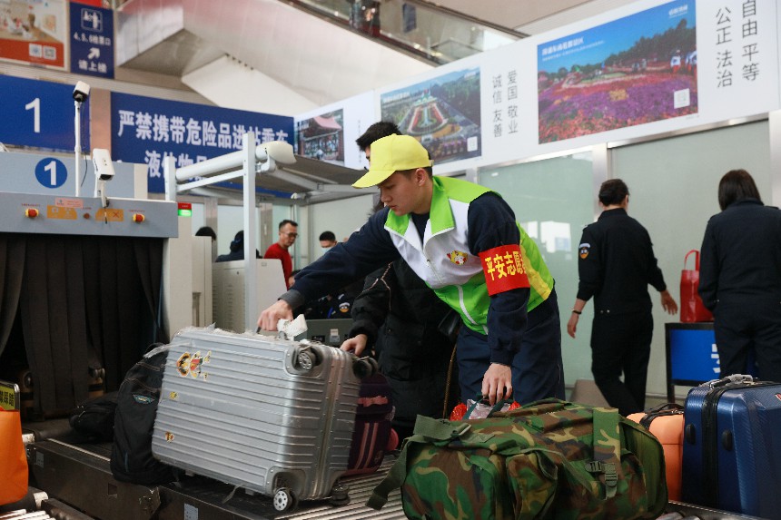 漳州车务段志愿者“青小柠”在安检口帮助旅客拿大件行李。陈明摄