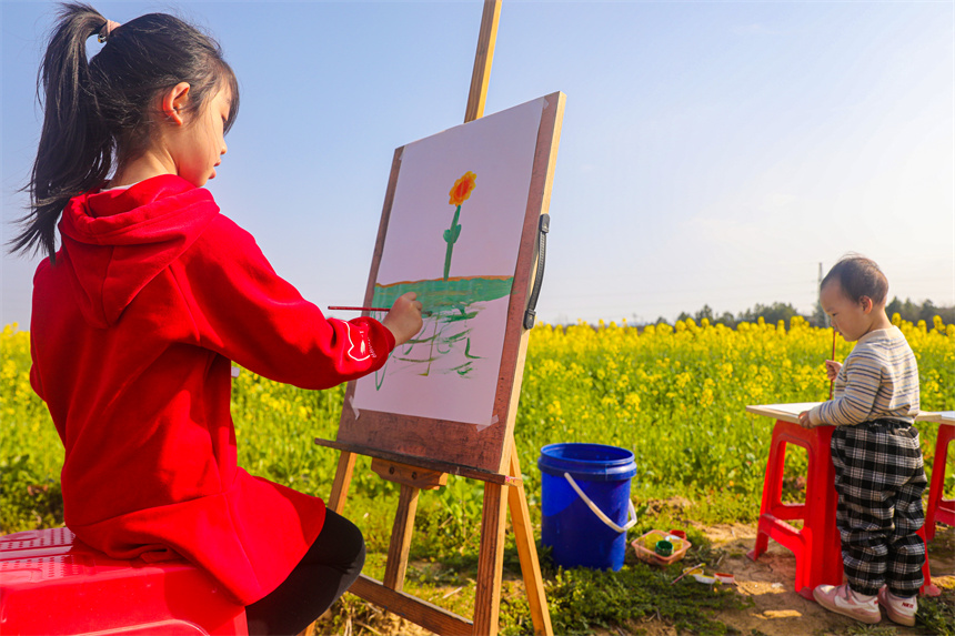 孩子們在油菜花地裡作畫。李煜祖攝