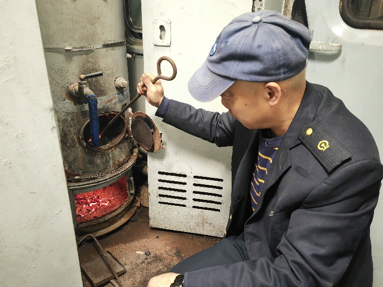 杨师傅正在用工具通炉子，火一下就烧旺了。朱烁昕摄