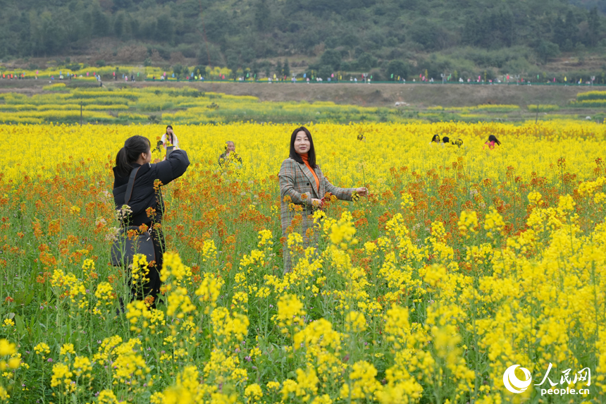 游客在油菜花海中打卡拍照。人民網 孔文進攝