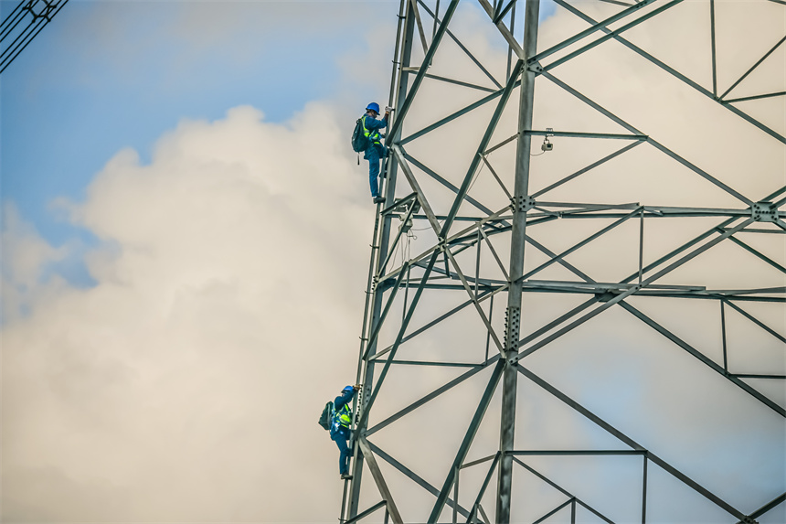 高空作業人員正在攀爬特高壓鐵塔。彭聲彬攝