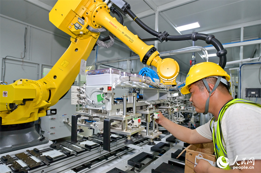 贛州經開區新能源科技城的一家動力電池生產企業，技術工人在調試新安裝的智能機械臂。人民網 朱海鵬攝
