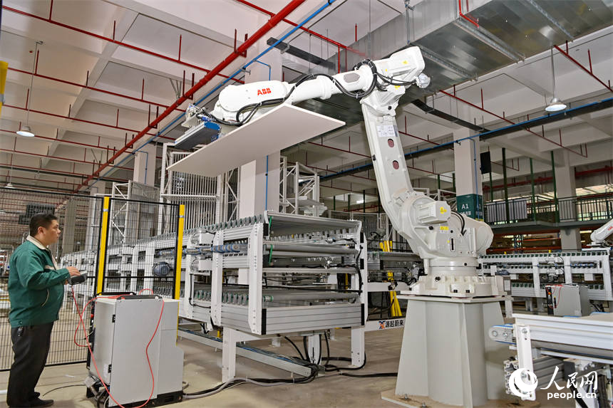 贛州市南康區的一家定制家具智能制造企業車間裡，工人在生產線上操作智能機器人加工板材。人民網 朱海鵬攝