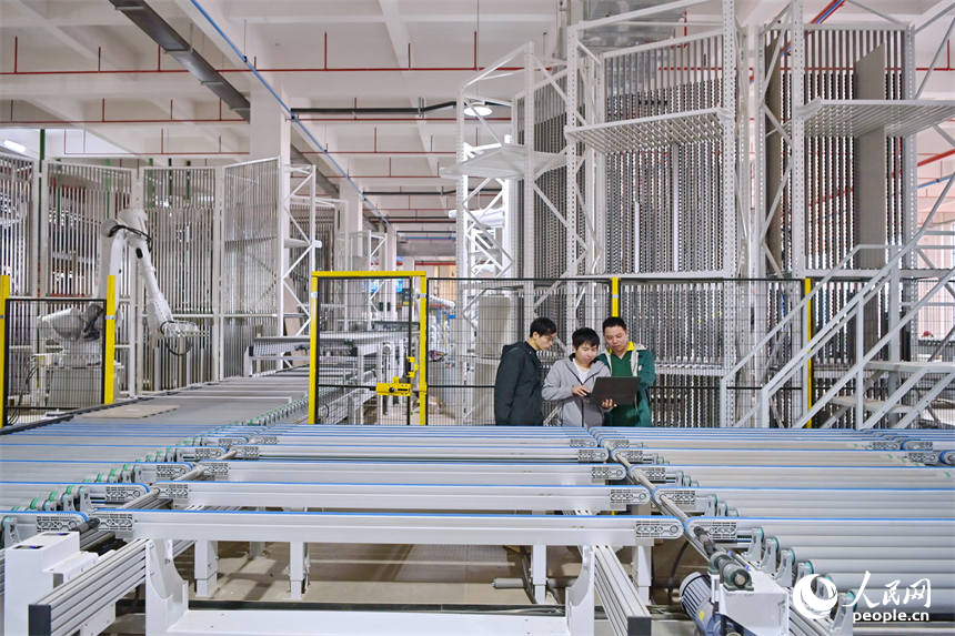 赣州市南康区的一家定制家具智能制造企业车间里，工人在生产线上操作智能机器人加工板材。人民网 朱海鹏摄
