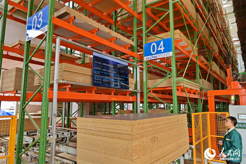 赣州市南康区的一家定制家具智能制造企业车间里，RGV自动导引车和堆垛机在智慧立体仓库来回存取板材。人民网 朱海鹏摄