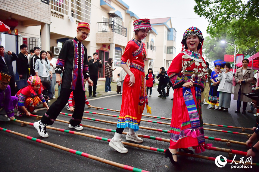 在洋林歸僑少數民族村，當地村民帶領外國友人跳竹竿舞。 人民網記者 時雨攝